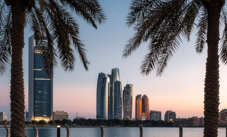 Abu Dhabi Corniche waterfront with calm beach, palm-lined promenade, and modern city skyline along the Arabian Gulf.