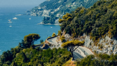 Amalfi Coast road view with winding coastal cliffs, pastel hillside villages, and sparkling Mediterranean sea under a clear s