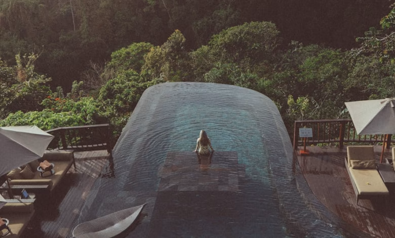 Luxury Bali wellness resort with tropical gardens, palm trees, and serene infinity pool overlooking lush green hills and a tr