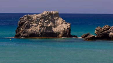 Pristine turquoise beach cove on a Greek island with white sand, rocky cliffs, and clear Aegean water in Greece, perfect for