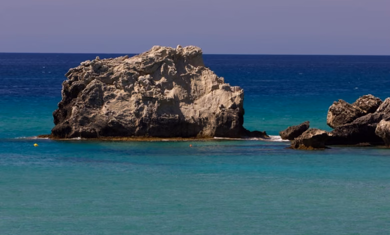 Pristine turquoise beach cove on a Greek island with white sand, rocky cliffs, and clear Aegean water in Greece, perfect for