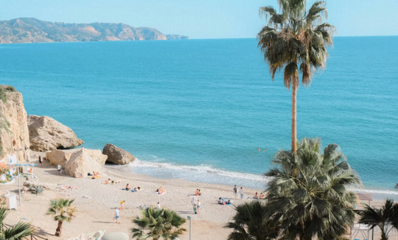 Golden sandy beach on the southern Spain coast with calm blue water, rocky cliffs, and a clear Mediterranean shoreline, ideal