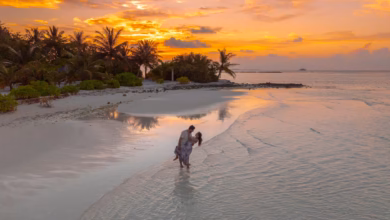 Sunset view of a romantic coastal destination with calm blue water, sandy beach, and scenic cliffs, ideal for couples vacatio