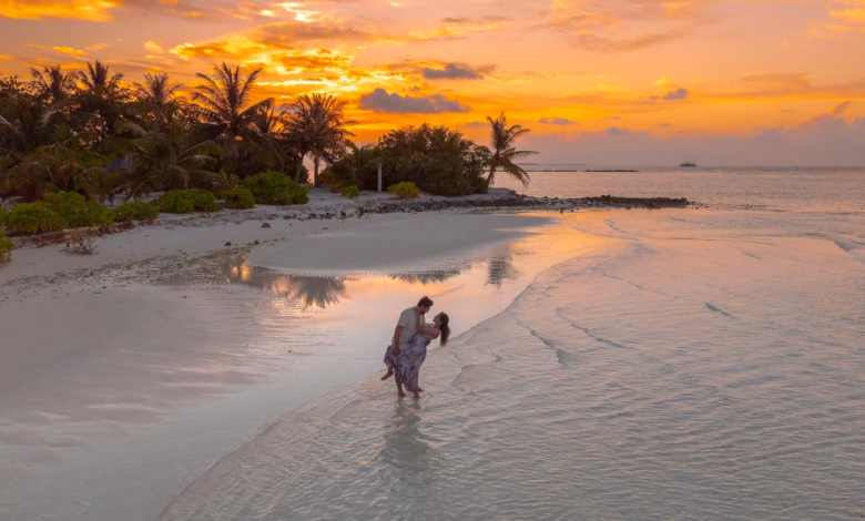 Sunset view of a romantic coastal destination with calm blue water, sandy beach, and scenic cliffs, ideal for couples vacatio