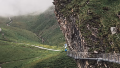 Snow-dusted Swiss Alps with a winding lakeside trail, turquoise water, and dramatic mountain scenery in Switzerland.