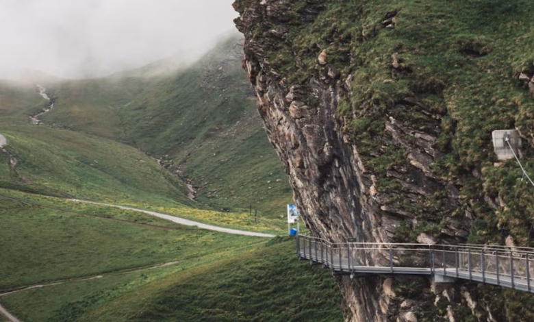 Snow-dusted Swiss Alps with a winding lakeside trail, turquoise water, and dramatic mountain scenery in Switzerland.