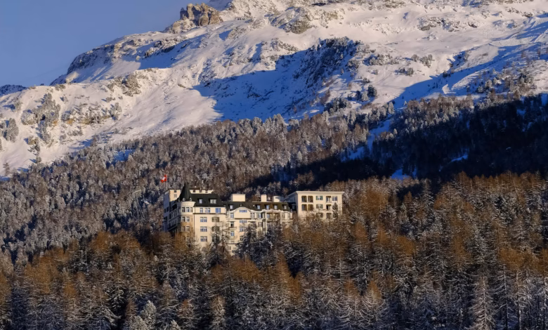 Elegant Switzerland luxury hotel overlooking snow-capped Alpine peaks and a serene mountain valley, with a stunning lakeside