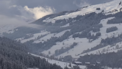 Snow-covered European winter village with cozy alpine chalets, snowy mountains, and a peaceful family holiday destination atm