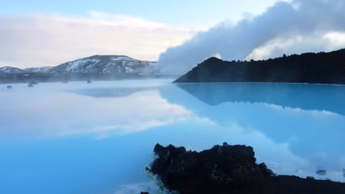 Blue Lagoon Iceland geothermal water surrounded by a volcanic landscape, with misty blue water, dark lava rock, and dramatic