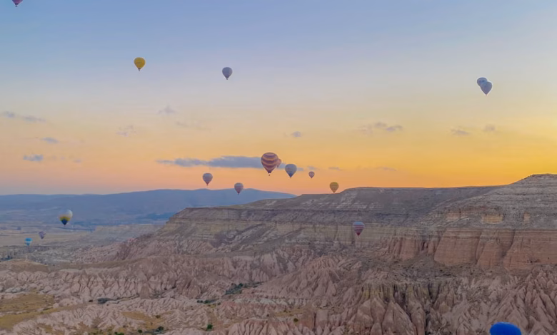 Cappadocia hot air balloons floating above fairy chimneys and the rugged sunrise landscape of central Turkey
