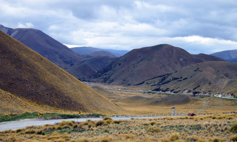 Scenic view of New Zealand South Island with dramatic mountains, a winding road, and lush lakeside landscapes showcasing New