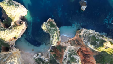Golden cliffs and turquoise water along the Algarve coast in Portugal, with rugged sea caves and a scenic Atlantic shoreline.