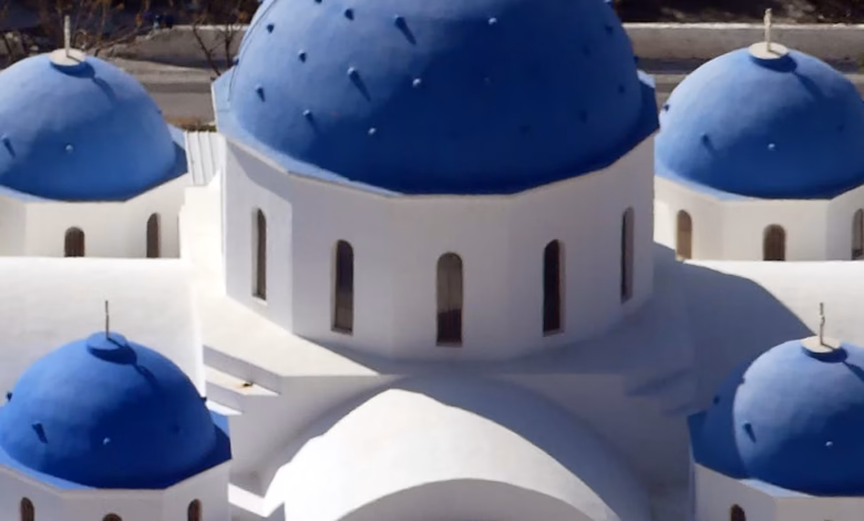 Scenic Greek Islands landscape with white buildings, blue domes, and a dramatic coastline overlooking the Mediterranean Sea.