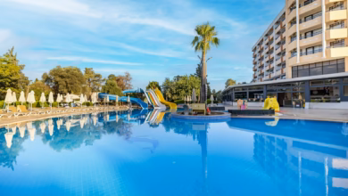 Modern family friendly hotel exterior near city attractions, with landscaped grounds, palm trees, and a bright urban skyline