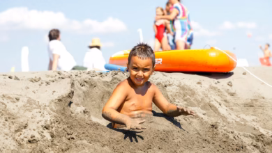 Calm family-friendly beach with soft sand, gentle waves, and a clear shoreline under bright sunshine.