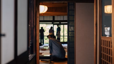 Traditional Kyoto tea house with wooden architecture beside a serene Japanese garden, stone path, and lush greenery in a peac