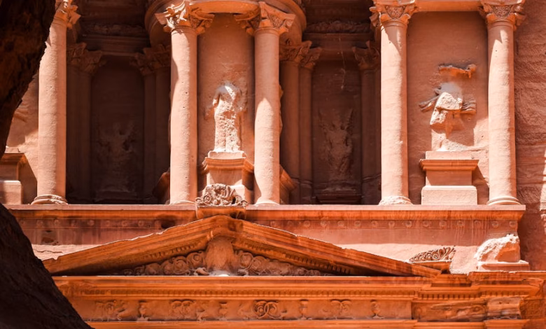 Petra Jordan treasury facade carved into rose-red sandstone cliffs, iconic ancient archaeological ruins in a dramatic desert