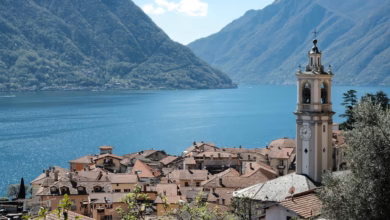 Scenic Lake Como village with colorful lakeside houses, calm blue water, and lush hills in northern Italy.