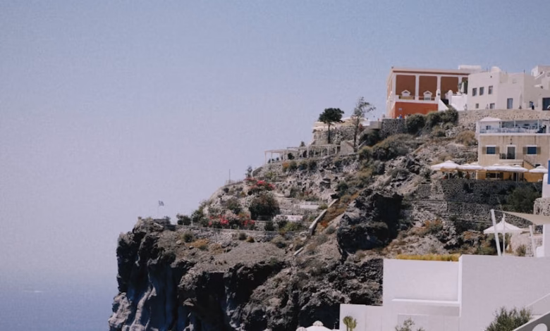 Whitewashed cliffside buildings with blue domes overlooking the caldera in Santorini, Greece, with the Aegean Sea and volcani