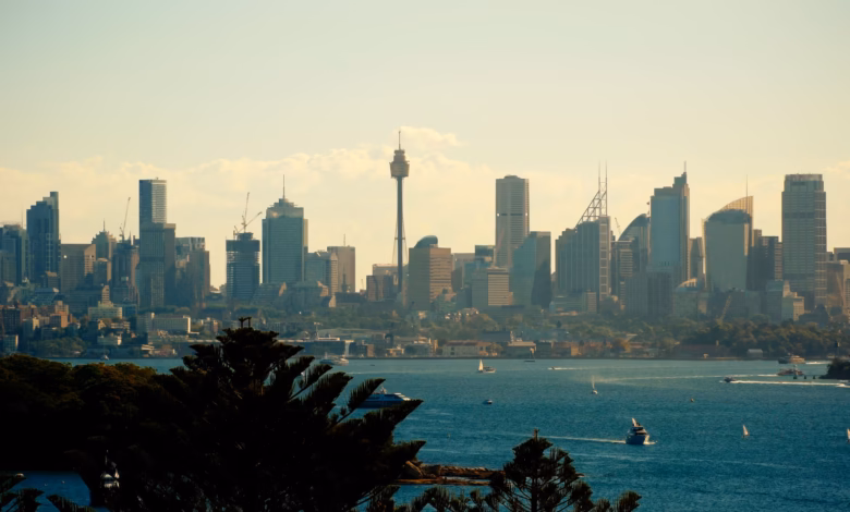 Sydney Harbor skyline with the Sydney Opera House, Harbour Bridge, and sparkling waterfront cityscape at sunset.