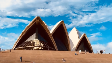 Sydney Opera House exterior with iconic white sail-shaped shells on Sydney Harbour, framed by waterfront skyline and blue wat