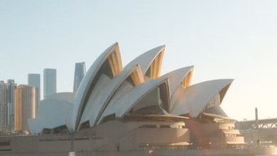 Sydney Opera House exterior with sail-like white shells overlooking Sydney Harbour and the waterfront skyline in Australia.