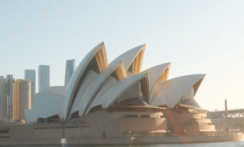 Sydney Opera House exterior with sail-like white shells overlooking Sydney Harbour and the waterfront skyline in Australia.